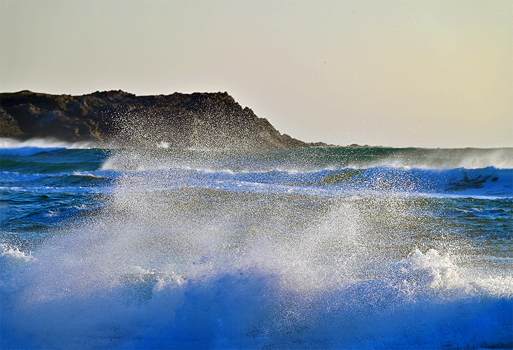 Picture of spray from waves being thrown into the air as the waves break when approaching a beach in a bay