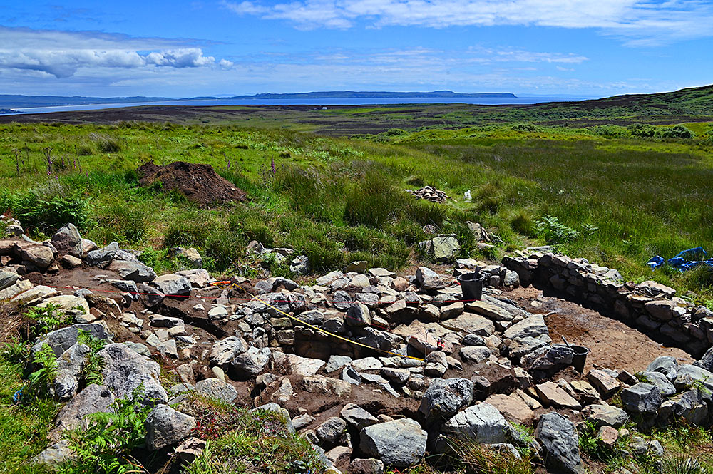 Picture of an archaeological dig on an elevated landscape with a wide view over a sea loch and distant lands